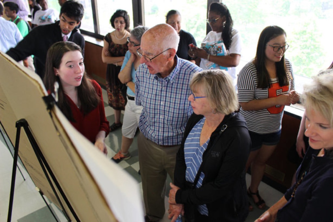 High school intern Halle Bristol presents her poster to Tom and Linda McCausland, whose generosity supports the high school intern program.